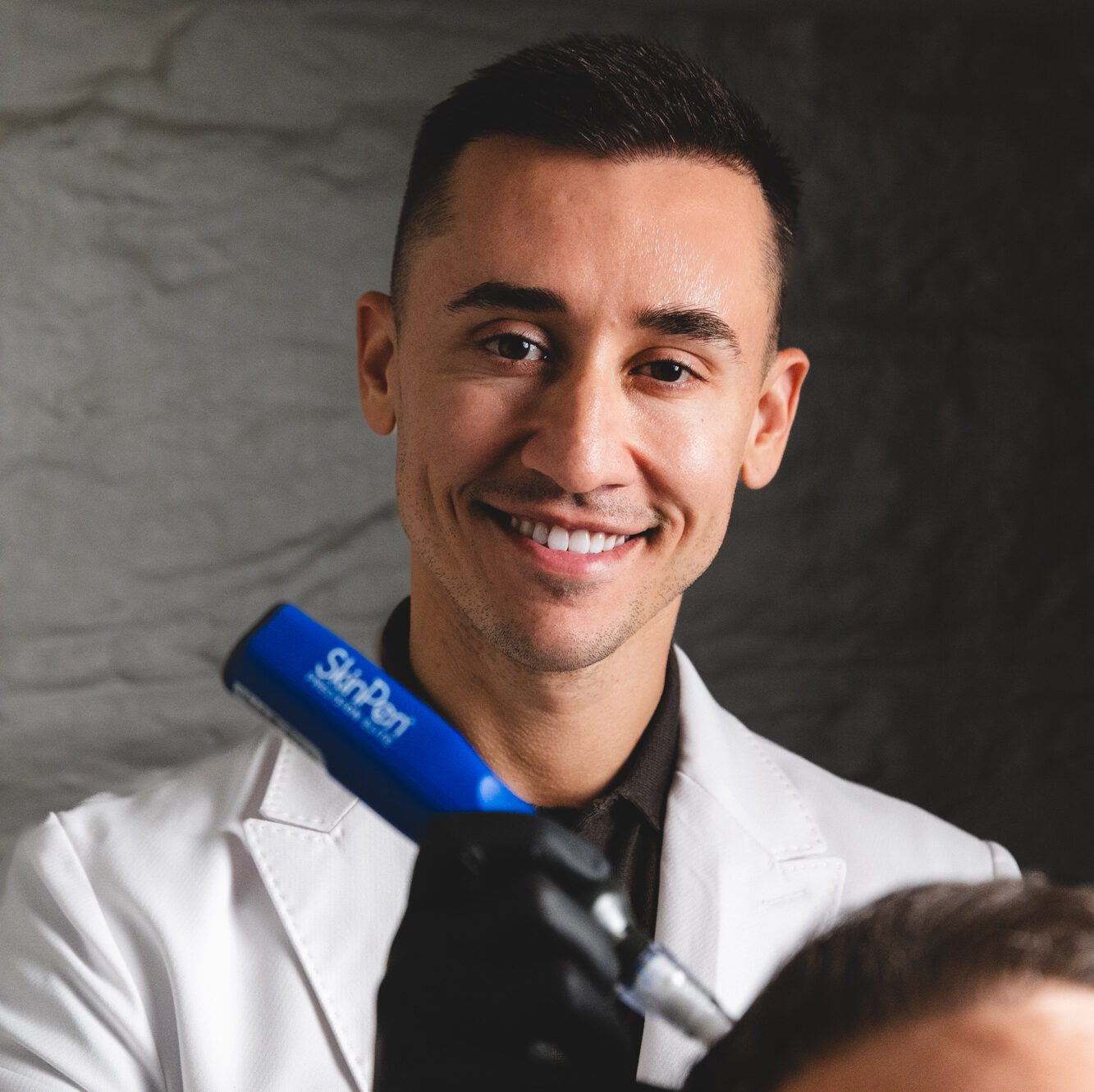 A member of our team smiles as he performs collagen induction therapy in New York City